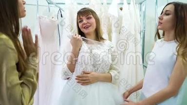 年轻女孩和朋友在婚纱沙龙中选择婚纱